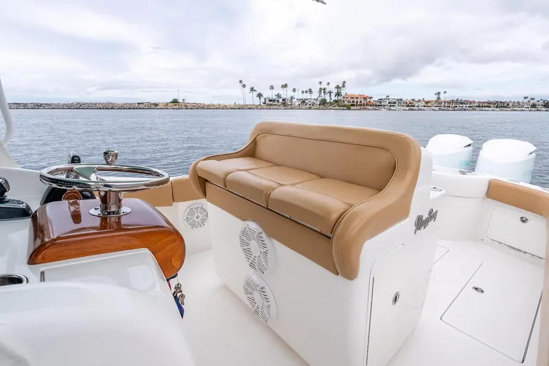 Slide: The Image of 2015 Mag Bay 33 CC boat interior with tan seating and steering wheel, overlooking calm waters. - 16