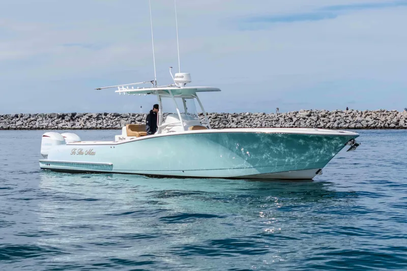 Slide: The Image of 2015 Mag Bay 33 CC boat on calm water near rocky shoreline. - 2