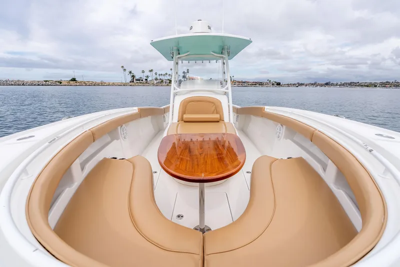 Slide: The Image of 2015 Mag Bay 33 CC boat with tan seating and wooden table on calm water. - 21