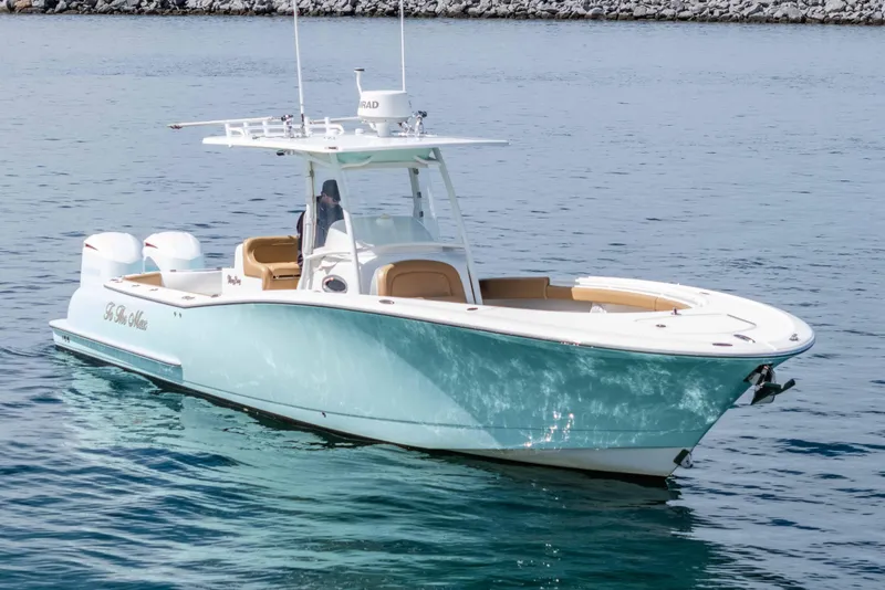 Slide: The Image of 2015 Mag Bay 33 CC boat on calm water, featuring sleek design and twin engines. - 3