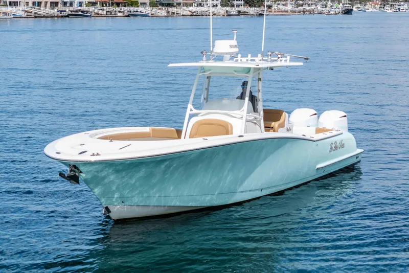 Slide: The Image of 2015 Mag Bay 33 CC boat on calm water, featuring sleek design and twin engines. - 5