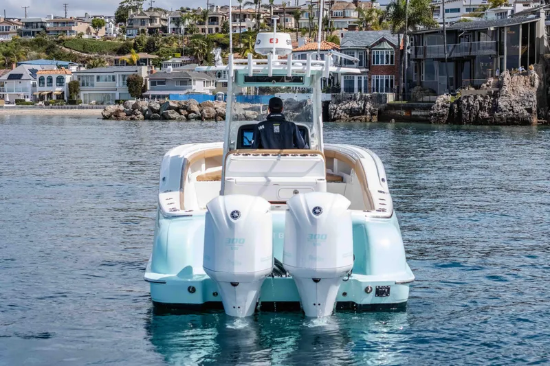 Slide: The Image of 2015 Mag Bay 33 CC boat with dual engines on calm water near coastal homes. - 9