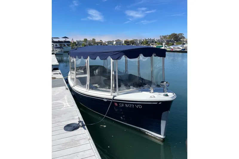 The Image of 2012 Duffy Bay Island 22 electric boat docked in a marina under clear blue skies. - 1