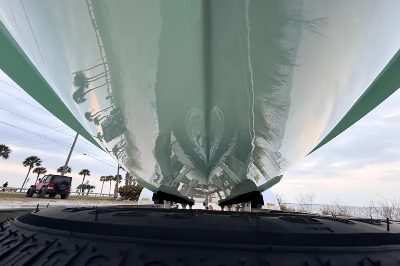 Slide: The Image of Underneath view of a 2025 Hell's Bay Professional boat on a trailer, with palm trees in the background. - 10