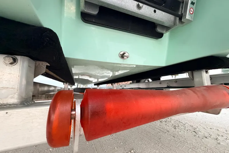 Slide: The Image of Underneath view of a 2025 Hell's Bay Professional boat on a trailer with red rollers. - 18