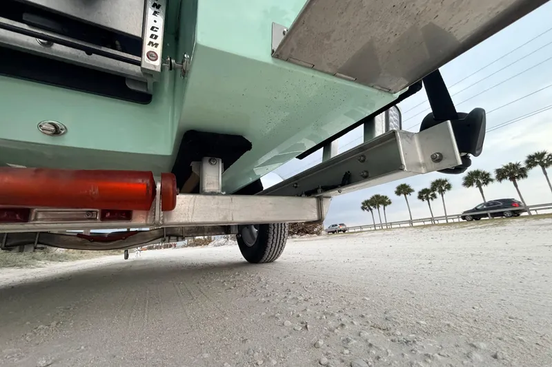 Slide: The Image of Underneath view of a 2025 Hell's Bay Professional boat trailer on a sandy road. - 20