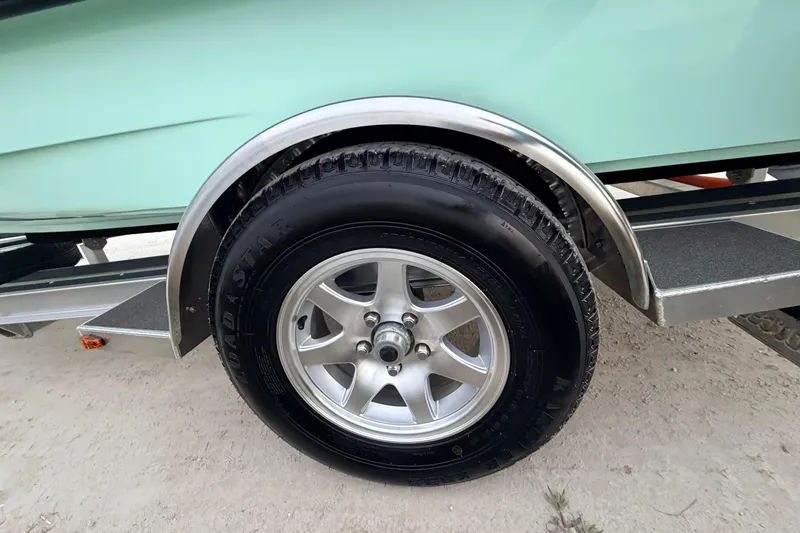 Slide: The Image of Trailer wheel of 2025 Hell's Bay Professional boat on sandy ground. - 24