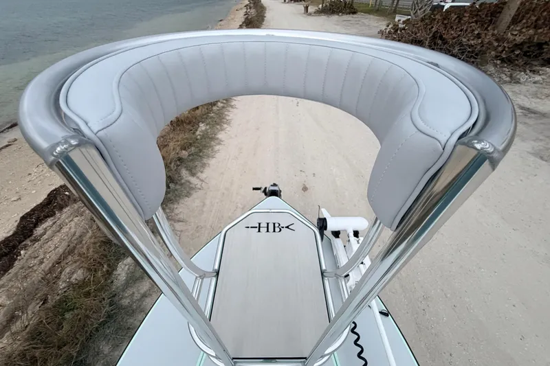 Slide: The Image of 2025 Hell's Bay Professional boat with sleek design and cushioned seating, near a sandy shoreline. - 31