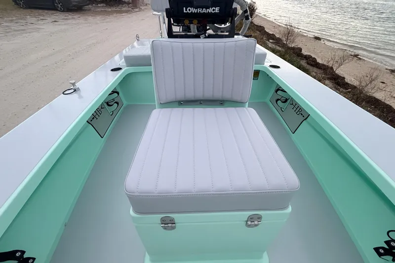 Slide: The Image of 2025 Hell's Bay Professional boat interior with cushioned seating and Lowrance equipment by the water. - 42