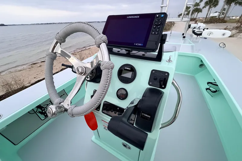 Slide: The Image of 2025 Hell's Bay Professional boat dashboard with steering wheel and navigation system by the shore. - 50