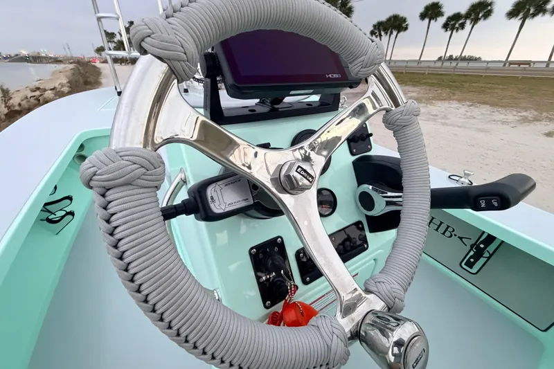 Slide: The Image of 2025 Hell's Bay Professional boat steering wheel with modern controls and coastal background. - 55