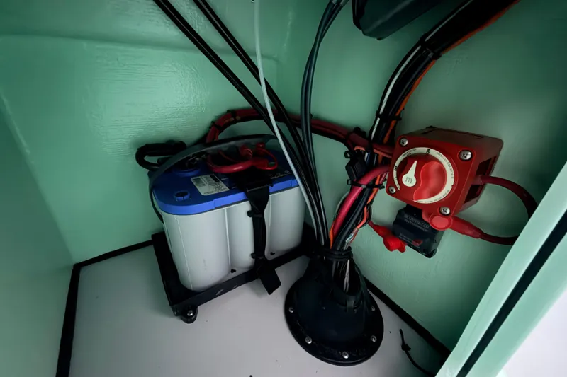 Slide: The Image of 2025 Hell's Bay Professional boat battery compartment with wiring and power switch. - 59