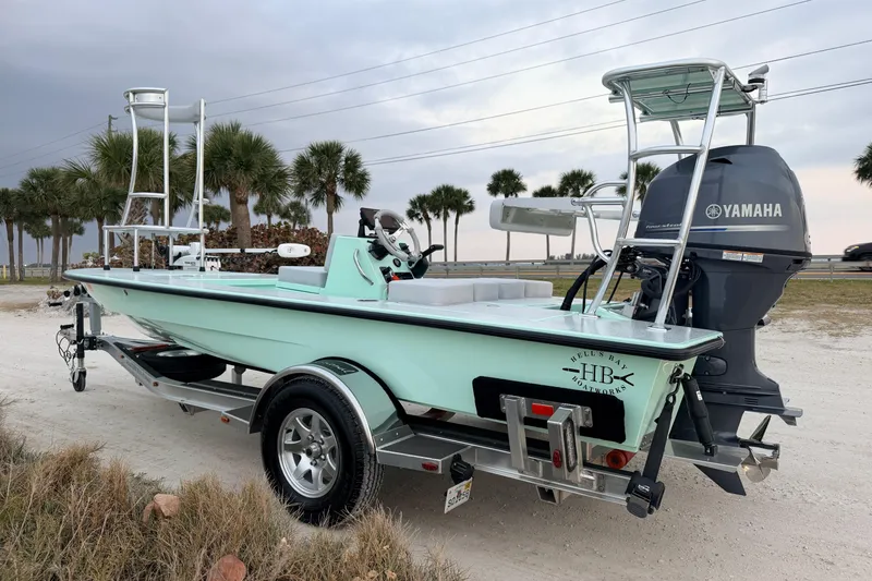 Slide: The Image of 2025 Hell's Bay Professional boat with Yamaha engine on a trailer, parked near palm trees. - 6