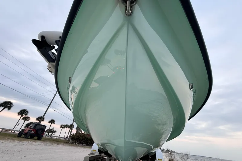Slide: The Image of 2025 Hell's Bay Professional boat on trailer, viewed from below, with cloudy sky backdrop. - 8
