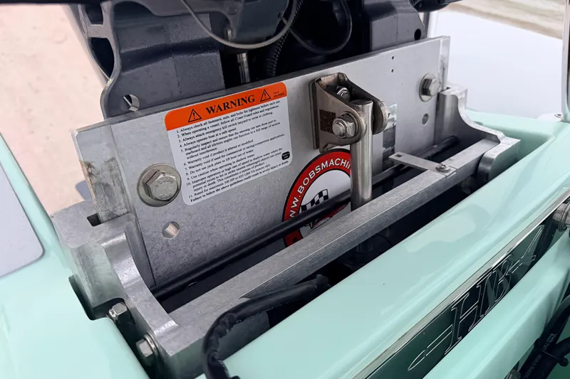 Slide: The Image of 2025 Hell's Bay Professional boat engine mount with warning label and metal components. - 80