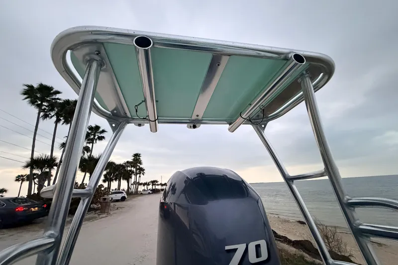 Slide: The Image of 2025 Hell's Bay Professional boat with T-top, parked near a beach with palm trees. - 84