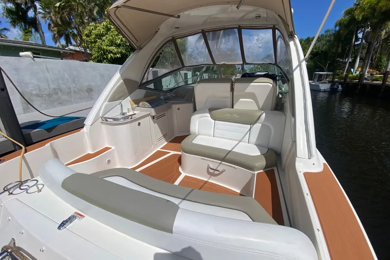 Slide: The Image of 2007 Sea Ray Sundancer 310 boat interior with seating and canopy, docked by lush greenery. - 28