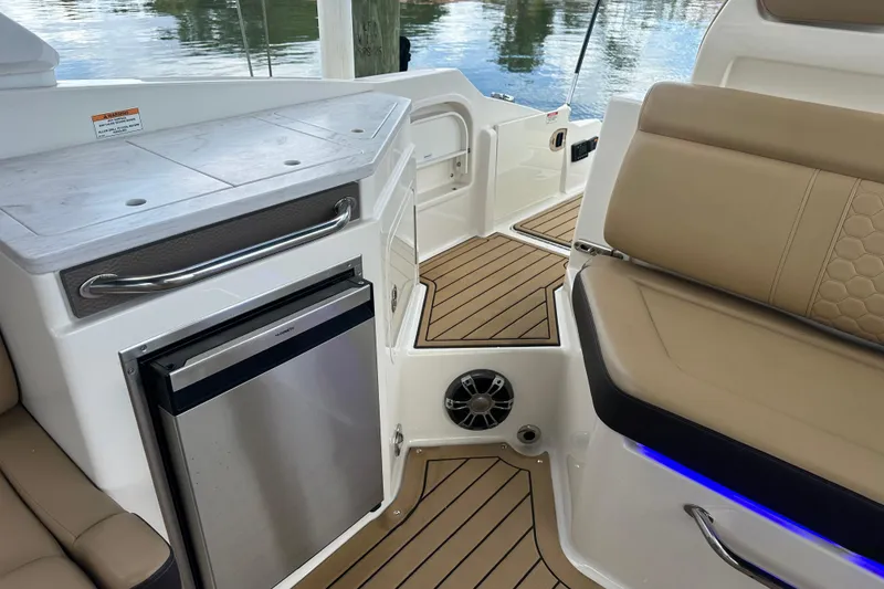 Slide: The Image of Interior of 2022 Sea Ray SDX 290 boat with seating, fridge, and wood flooring. - 10