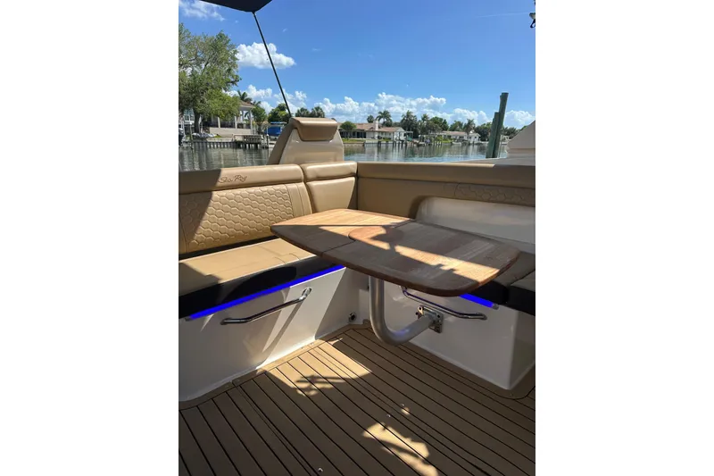 Slide: The Image of 2022 Sea Ray SDX 290 boat interior with tan seating and wooden table. - 13