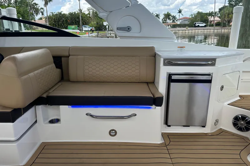 Slide: The Image of 2022 Sea Ray SDX 290 interior with tan seating, mini fridge, and wood-style flooring. - 9