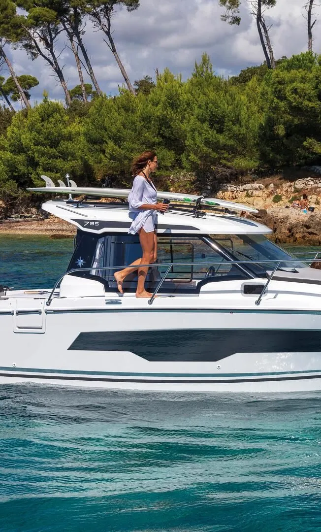 Slide: The Image of Woman on Jeanneau NC 795 Series 2 boat, 2025 model, in scenic coastal setting. - 5