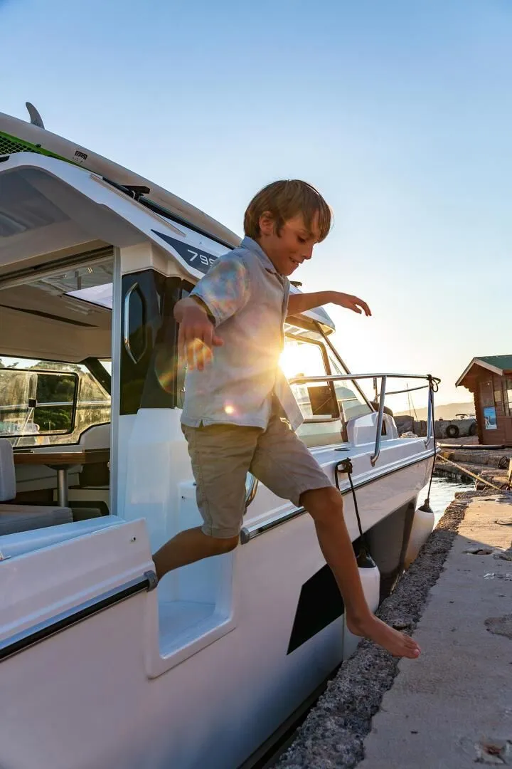 Slide: The Image of Child jumping off Jeanneau NC 795 Series 2 boat, sunset in background. - 7
