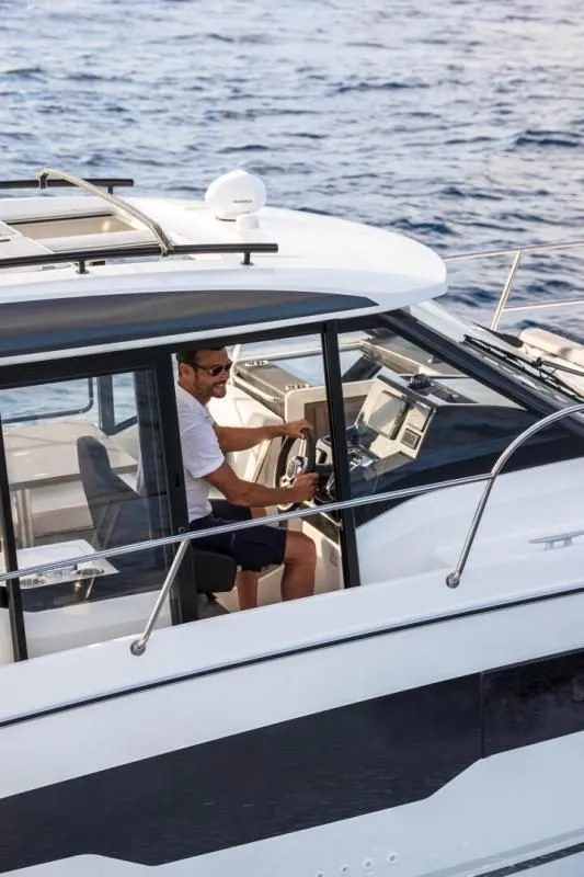 Slide: The Image of Man steering Jeanneau NC 895 S2 boat on open sea. - 13