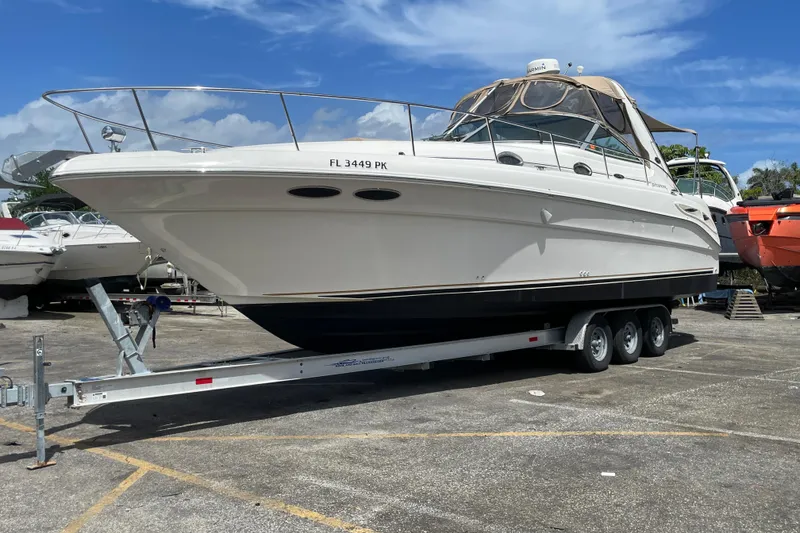 The Image of 2002 Sea Ray 340 Sundancer boat on a trailer under a clear blue sky. - 11
