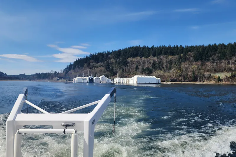 Slide: The Image of Boat wake view from 2003 Meridian 411 Sedan, with forested shoreline and buildings in the background. - 35