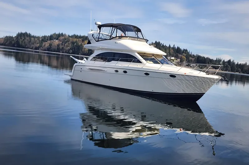 Slide: The Image of 2003 Meridian 411 Sedan yacht on calm water with forested shoreline background. - 43