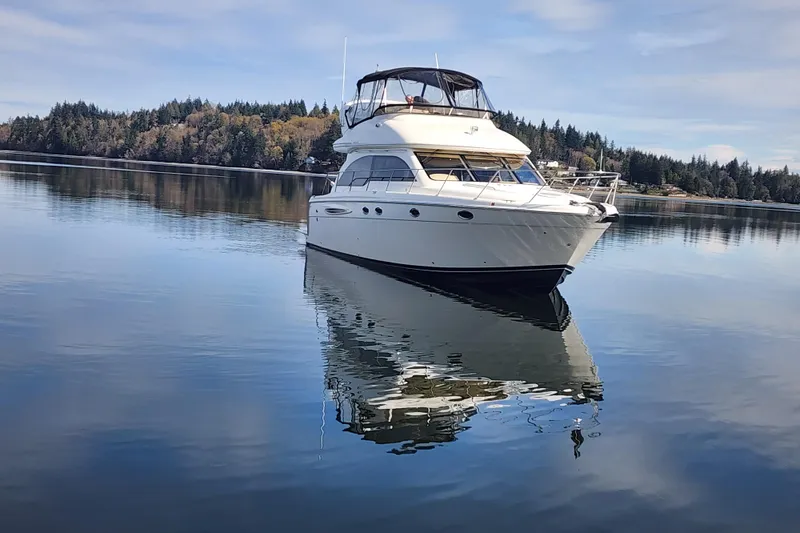 Slide: The Image of 2003 Meridian 411 Sedan yacht on calm water with forested shoreline background. - 44