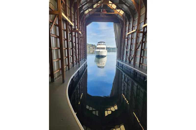 Slide: The Image of 2003 Meridian 411 Sedan yacht docked in a boathouse, reflecting on calm water. - 51