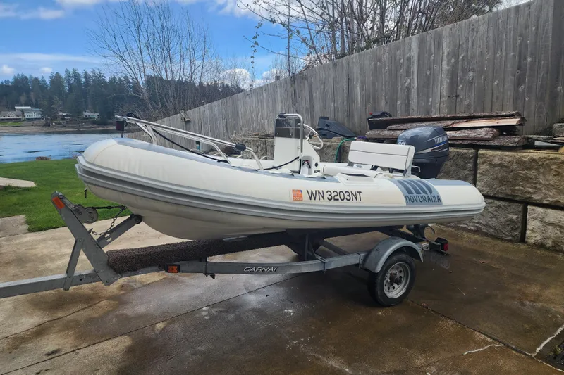 Slide: The Image of Inflatable boat on trailer with Yamaha motor, parked near a lake, overcast sky. - 66