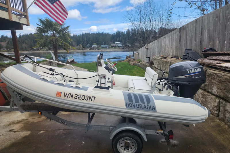 Slide: The Image of Novurania inflatable boat with Yamaha motor on trailer, near waterfront, under American flag. - 67
