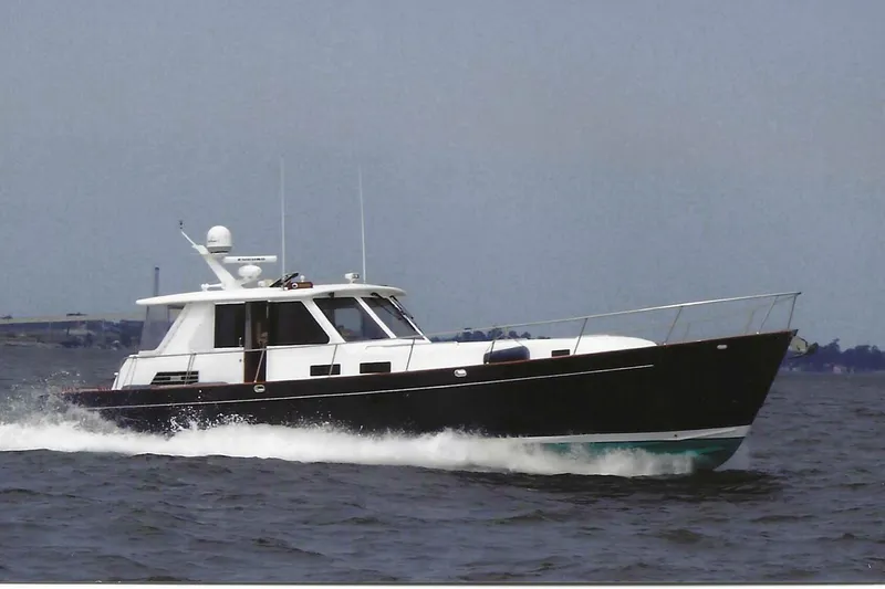 The Image of Legacy Yachts 52 Express 2002 cruising on a serene lake with lush green trees. - 0