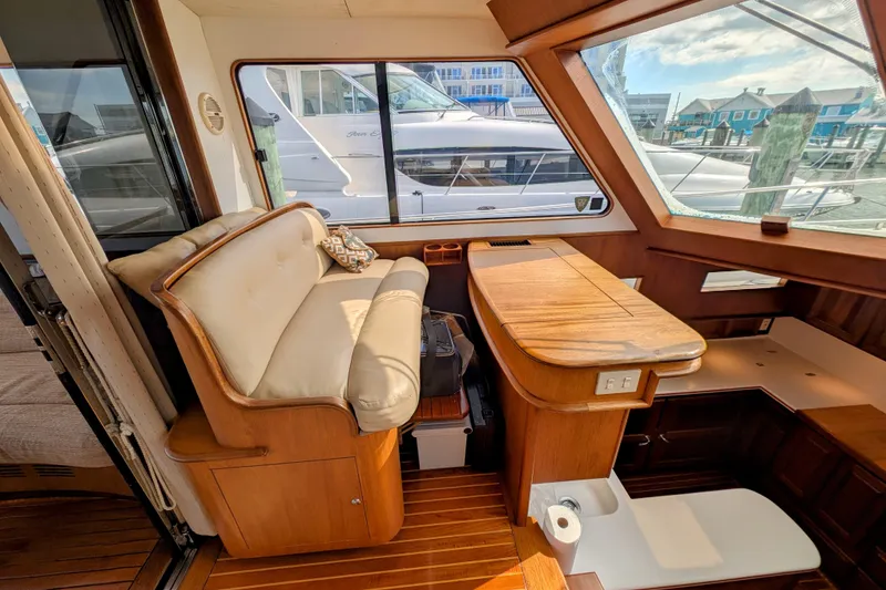 Slide: The Image of Interior of 2002 Legacy Yachts 52 Express with wooden seating and table, docked at marina. - 16