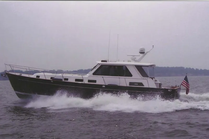 Slide: The Image of Legacy Yachts 52 Express 2002 boat named "Reunion" on water near forested shoreline. - 2