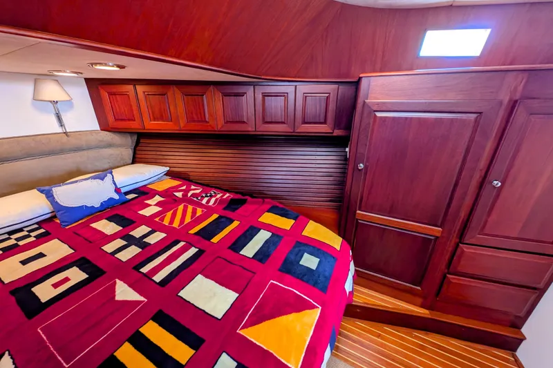 Slide: The Image of Cozy cabin interior of 2002 Legacy Yachts 52 Express with vibrant bedding and wooden cabinetry. - 25