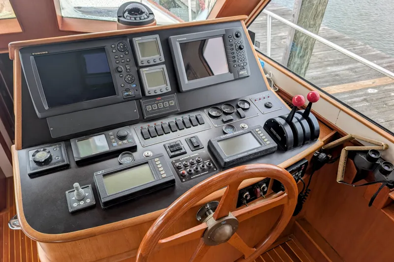 Slide: The Image of Control panel of a 2002 Legacy Yachts 52 Express with navigation instruments and steering wheel. - 31