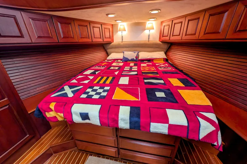 Slide: The Image of Luxurious 2002 Legacy Yachts 52 Express cabin with nautical-themed bedding and elegant wood paneling. - 40