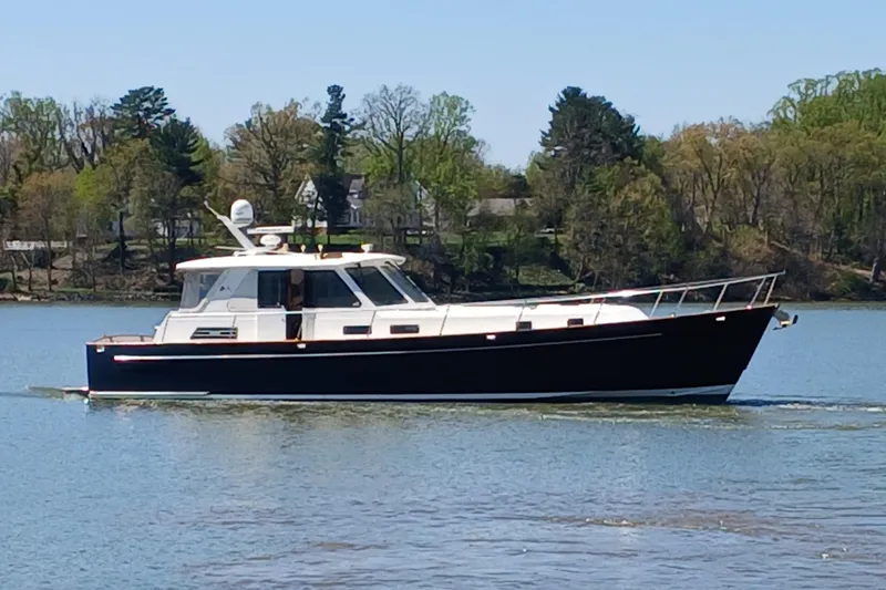 Slide: The Image of 2002 Legacy Yachts 52 Express cruising on a serene lake with lush green trees. - 6