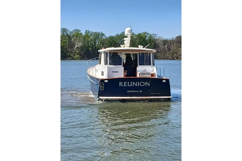 Slide: The Image of Legacy Yachts 52 Express 2002 cruising on a serene lake with lush green trees. - 7