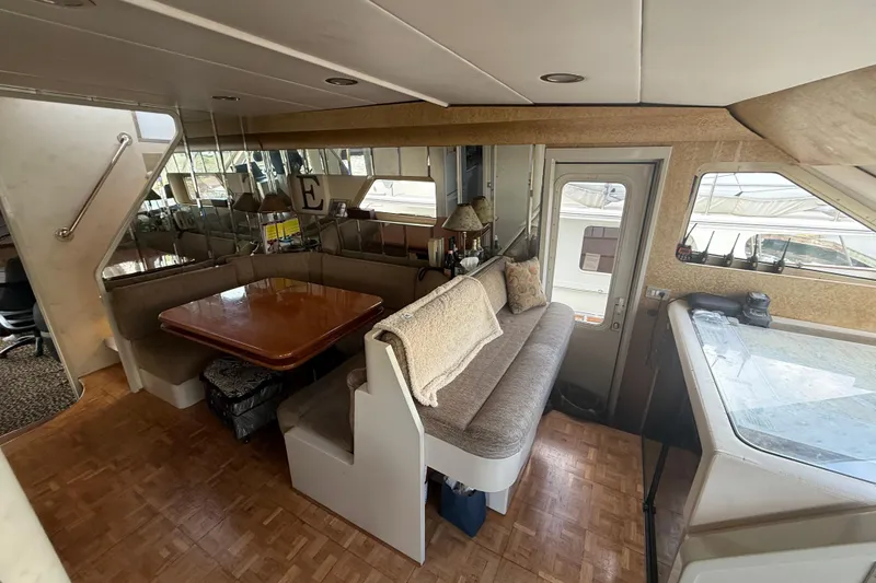 Slide: The Image of 1988 Maiora Motor Yacht interior with dining area, mirrored walls, and cozy seating. - 11