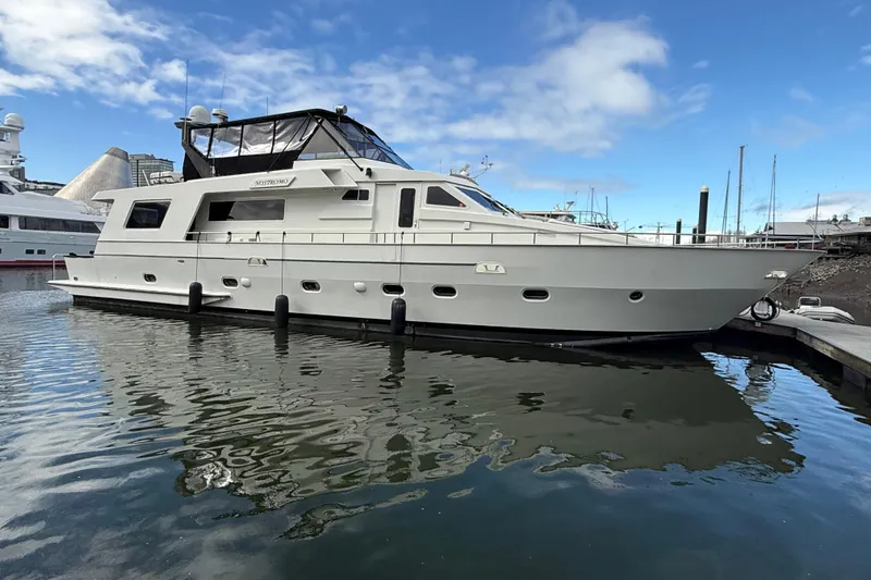 Slide: The Image of 1988 Maiora Motor Yacht docked in marina, reflecting on calm water under blue sky. - 2