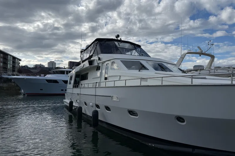 Slide: The Image of 1988 Maiora Motor Yacht docked under cloudy sky, with cityscape in background. - 4