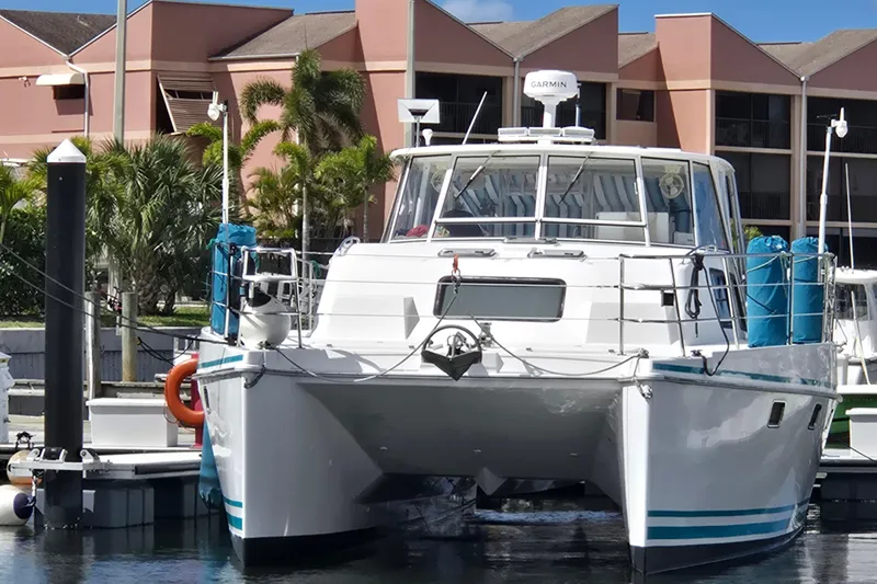 Slide: The Image of 2003 Endeavour Trawler Cat 44 docked at marina with palm trees and buildings in background. - 114