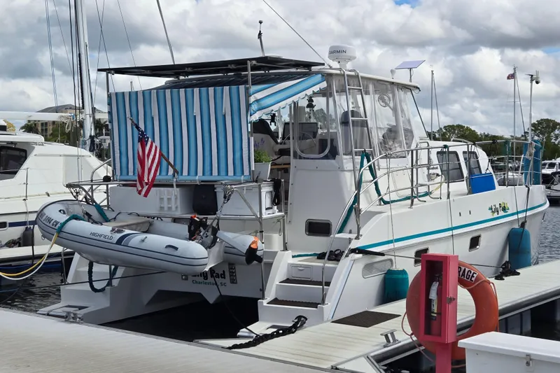 Slide: The Image of 2003 Endeavour Trawler Cat 44 docked, featuring striped canopy and American flag. - 116