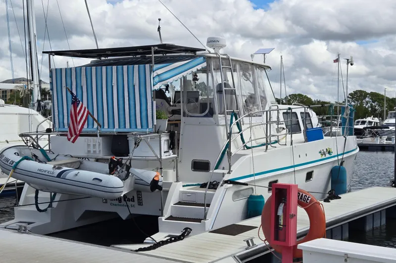 Slide: The Image of 2003 Endeavour Trawler Cat 44 docked, featuring striped canopy and American flag. - 2