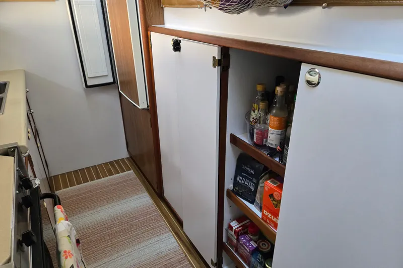 Slide: The Image of Kitchen storage area in a 2003 Endeavour Trawler Cat 44, featuring cabinets and pantry items. - 51
