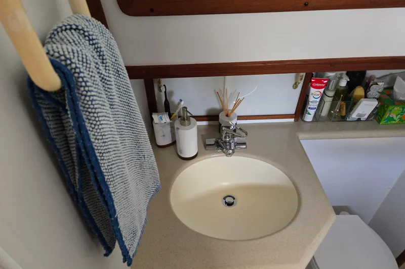 Slide: The Image of Bathroom sink area in 2003 Endeavour Trawler Cat 44, featuring toiletries and a striped towel. - 69